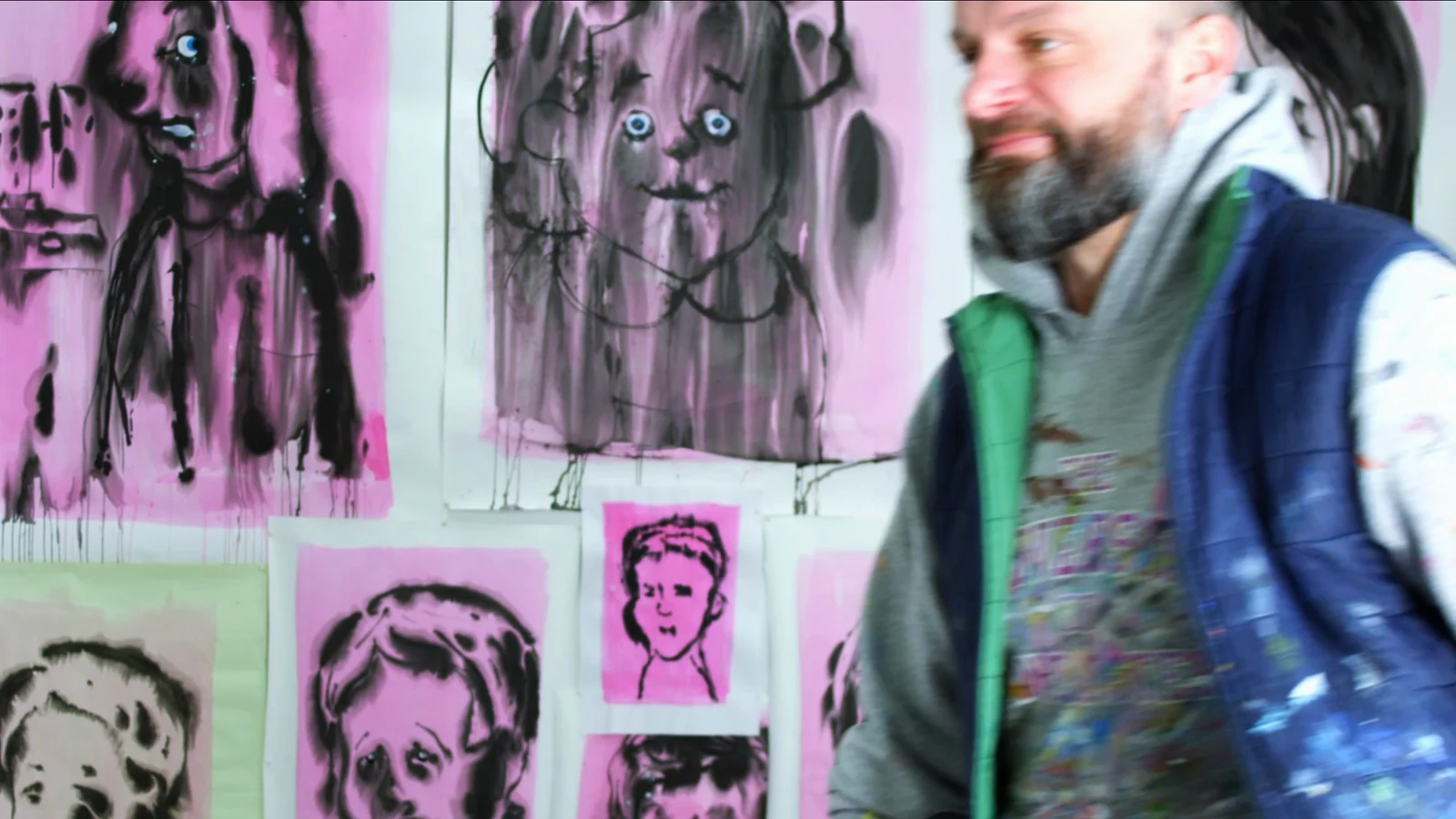 Erik walking past a wall of his drawings in the studio