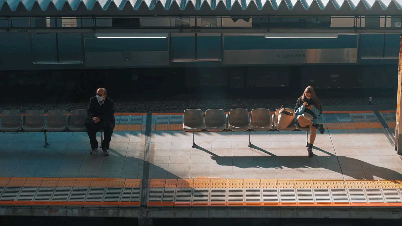 Two people on a station platform in low sun